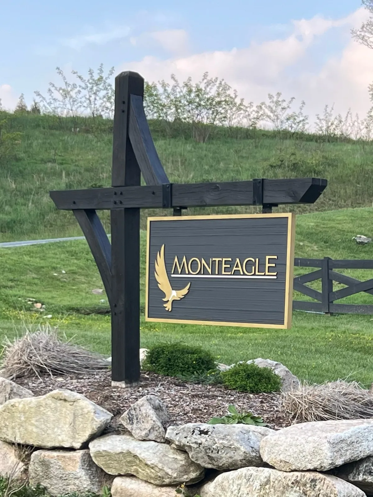 A welcoming exterior view of the property sign labeled 'MONTEAGLE,' complemented by an eagle motif and surrounded by landscaped stones and lush plants. The sign sits at the entrance, setting a sense of arrival and hinting at the natural beauty and adventure that await beyond.